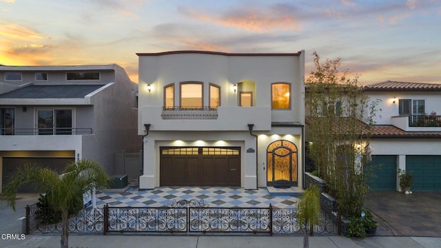 mediterranean / spanish-style home featuring a fenced front yard, a balcony, a garage, and stucco siding