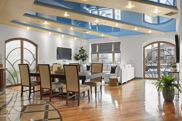 dining space featuring arched walkways, wood finished floors, and visible vents