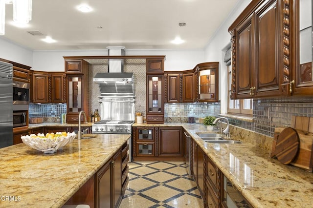 kitchen with appliances with stainless steel finishes, a sink, wall chimney exhaust hood, and tasteful backsplash