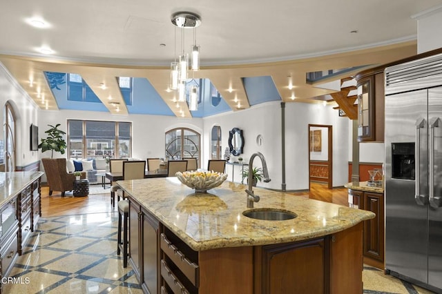 kitchen with arched walkways, ornamental molding, a sink, and stainless steel built in fridge