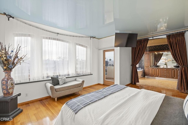 bedroom featuring a towering ceiling, baseboards, and wood finished floors