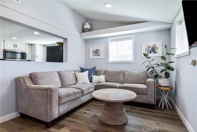 living room featuring lofted ceiling, baseboards, wood finished floors, and recessed lighting