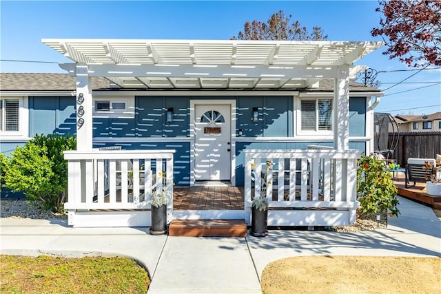 view of front of home with covered porch, fence, and a pergola