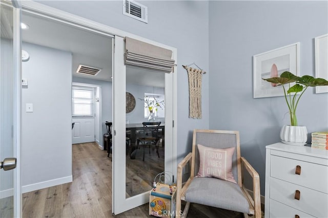 living area featuring baseboards, visible vents, and wood finished floors