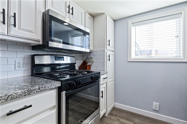 kitchen featuring baseboards, white cabinets, stainless steel microwave, dark wood-type flooring, and gas stove