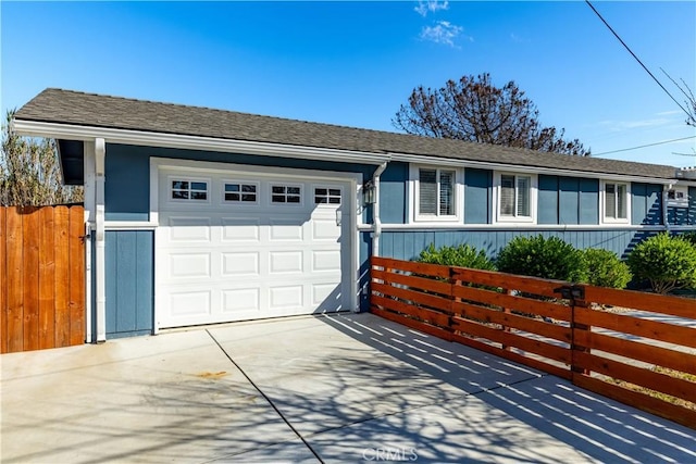 ranch-style house featuring a garage, a shingled roof, fence, and concrete driveway