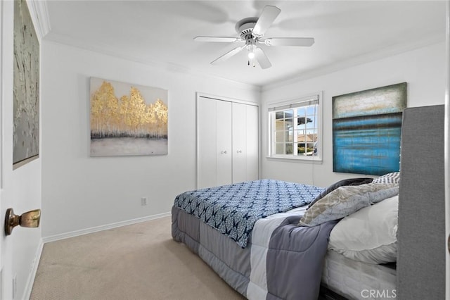 carpeted bedroom with baseboards, ceiling fan, a closet, and crown molding