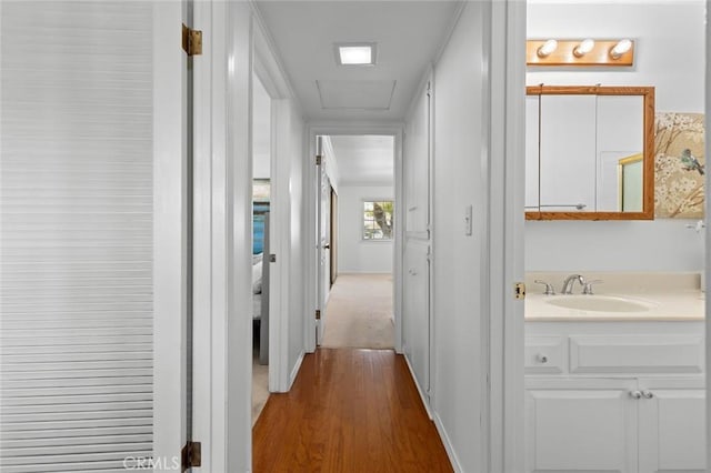 hallway featuring a sink and wood finished floors