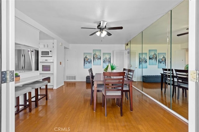 dining space with ceiling fan, visible vents, and wood finished floors