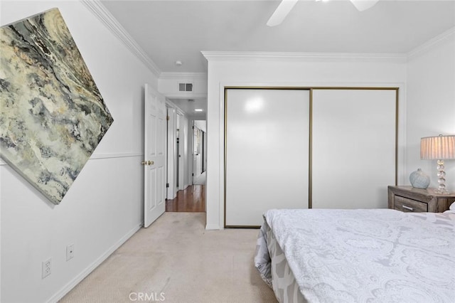 bedroom with ceiling fan, light carpet, visible vents, ornamental molding, and a closet