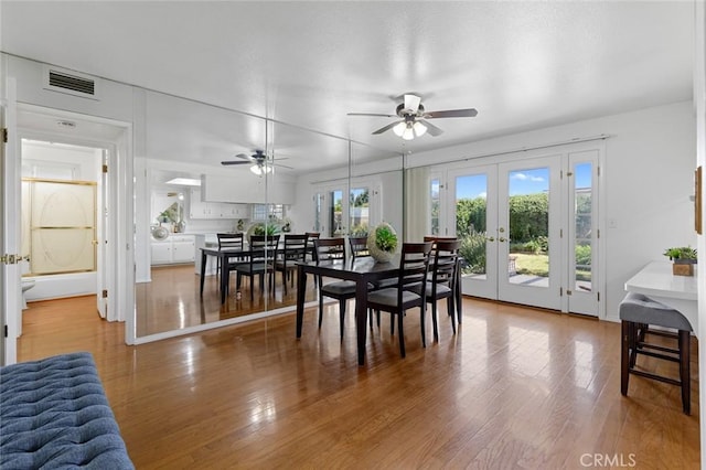 dining space with french doors, visible vents, ceiling fan, and wood finished floors