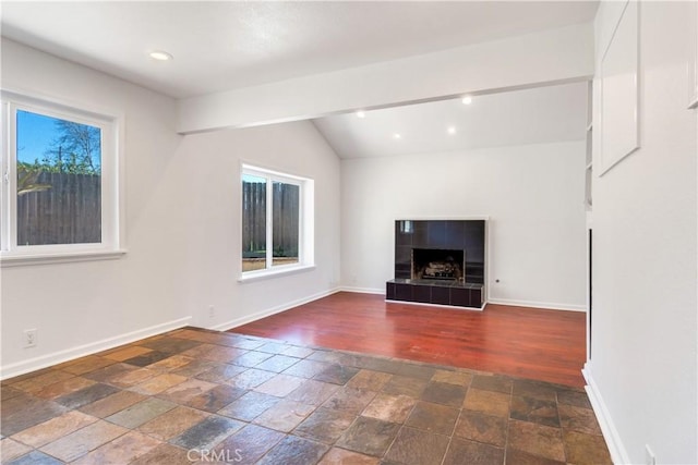 unfurnished living room with recessed lighting, a fireplace, stone tile flooring, and baseboards