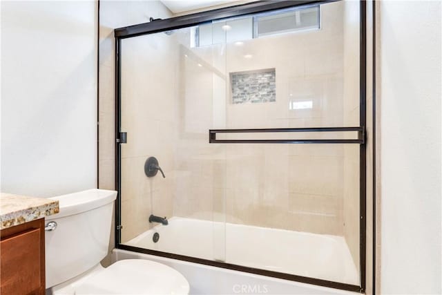 bathroom with enclosed tub / shower combo, vanity, and toilet