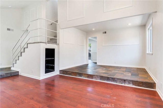 interior space with visible vents, a towering ceiling, and wood finished floors