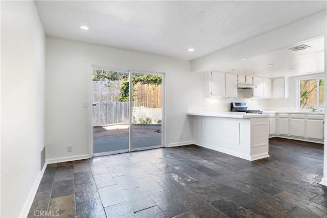 kitchen featuring stainless steel range oven, visible vents, baseboards, and white cabinetry