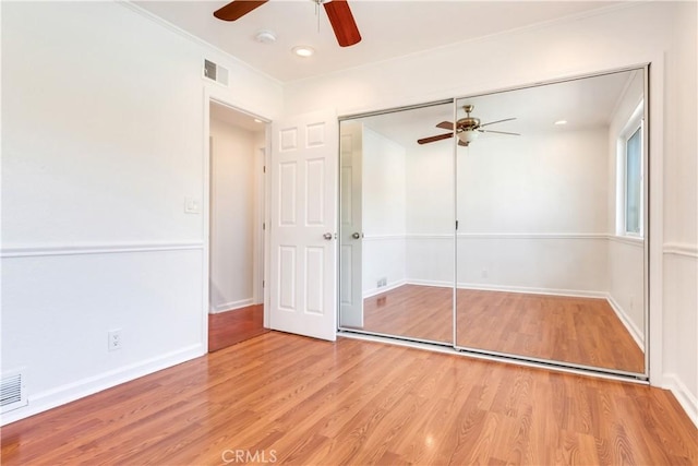 unfurnished bedroom featuring a closet, visible vents, a ceiling fan, wood finished floors, and baseboards