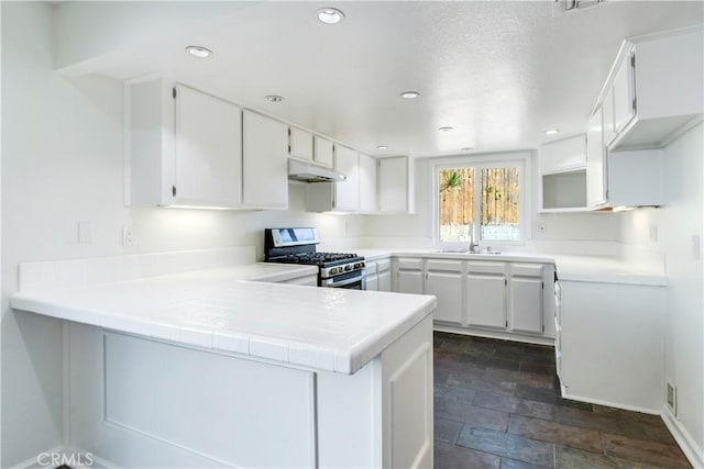 kitchen featuring recessed lighting, under cabinet range hood, a peninsula, a sink, and stainless steel range with gas stovetop