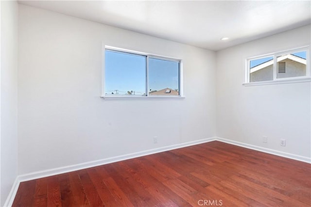 spare room with baseboards and wood finished floors