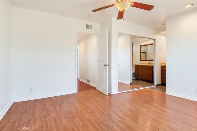 unfurnished room featuring baseboards, visible vents, a sink, and light wood finished floors