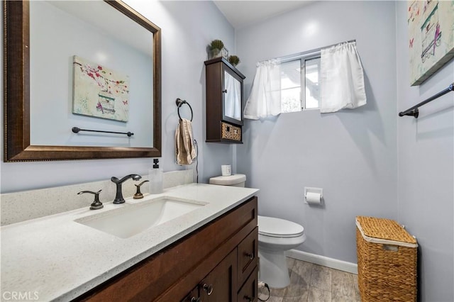 bathroom with baseboards, vanity, toilet, and wood finished floors