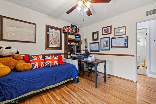 bedroom featuring a textured ceiling, wood finished floors, visible vents, and baseboards