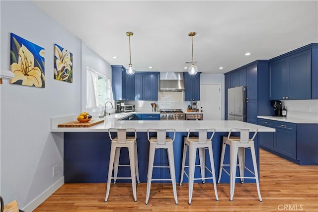 3104 Altura Ave, La Crescenta, CA 91214 - kitchen with blue cabinetry, wall chimney exhaust hood, freestanding refrigerator, a peninsula, and stainless steel gas range