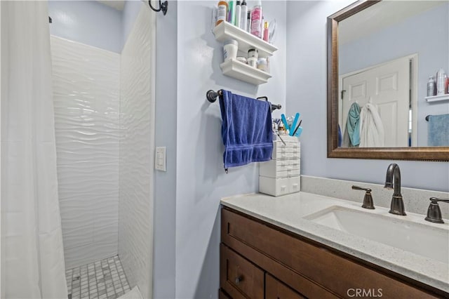 bathroom with tiled shower and vanity