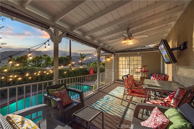 view of patio featuring a fenced in pool, a mountain view, an outdoor hangout area, and a ceiling fan