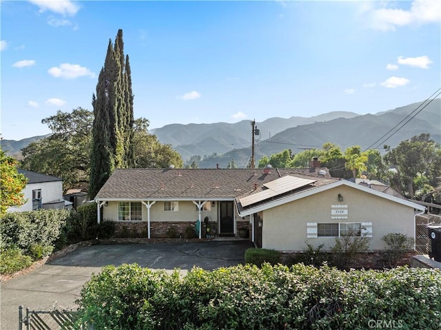 ranch-style home with driveway, a mountain view, and stucco siding