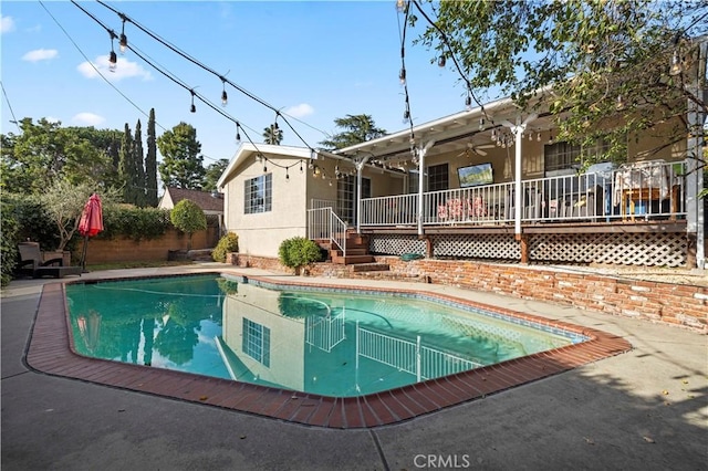 pool featuring a deck, a patio, fence, and a ceiling fan