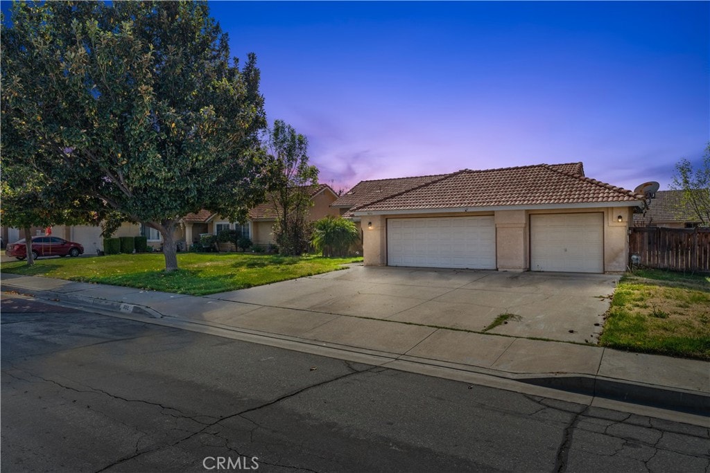 1652 Washington Ave, San Jacinto, CA 92583 - view of front of house with concrete driveway, a tile roof, an attached garage, a yard, and stucco siding