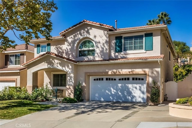 mediterranean / spanish home with a tile roof, a garage, driveway, and stucco siding