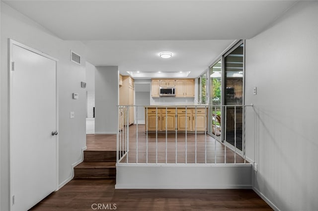 kitchen with light brown cabinets, baseboards, visible vents, dark wood-style flooring, and stainless steel microwave