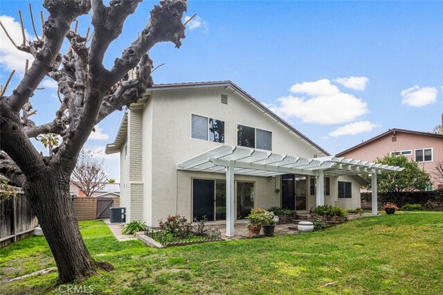 back of house featuring stucco siding, a lawn, a pergola, and fence