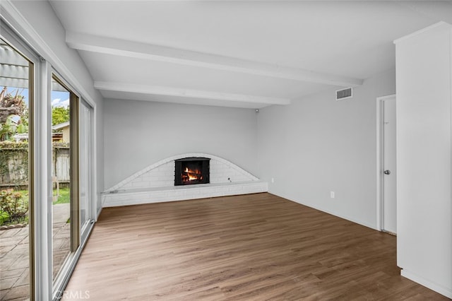 unfurnished living room featuring beam ceiling, visible vents, a brick fireplace, and wood finished floors