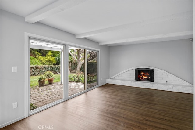 unfurnished living room featuring beamed ceiling, a fireplace, baseboards, and wood finished floors