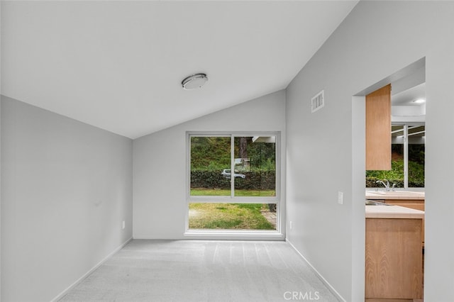 carpeted spare room with a sink, visible vents, lofted ceiling, and baseboards