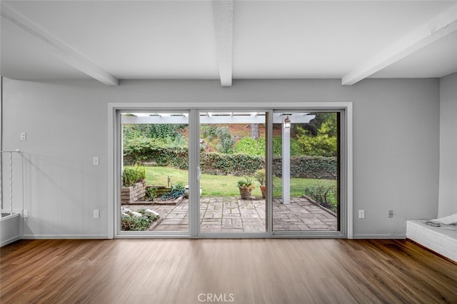 unfurnished living room with a wealth of natural light, beamed ceiling, and wood finished floors