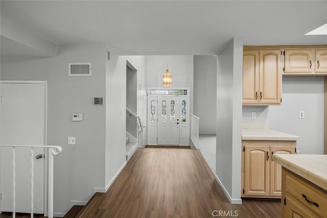 interior space featuring tile countertops, baseboards, visible vents, dark wood-style flooring, and light brown cabinetry