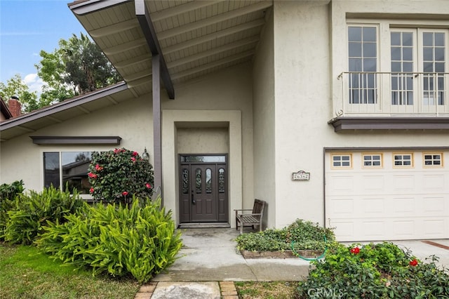 view of exterior entry with a garage and stucco siding