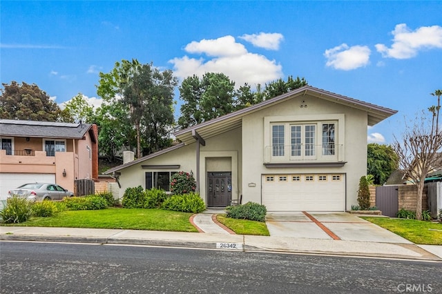 view of front of house featuring a front lawn, fence, concrete driveway, stucco siding, and a garage