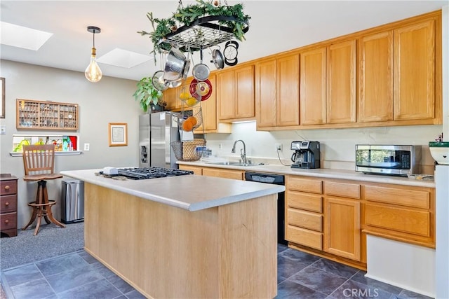 kitchen with light countertops, appliances with stainless steel finishes, a skylight, and a sink