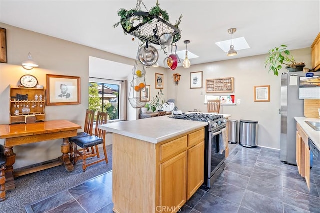 kitchen featuring appliances with stainless steel finishes, a skylight, light countertops, and a kitchen island