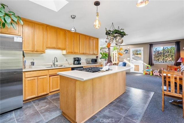 kitchen with a skylight, light countertops, dark carpet, appliances with stainless steel finishes, and a sink