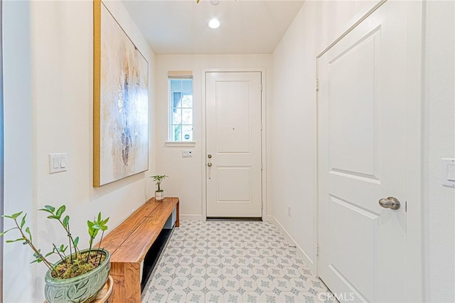 doorway to outside featuring light floors and baseboards