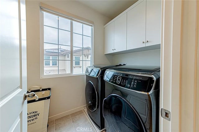 clothes washing area with baseboards, cabinet space, separate washer and dryer, and light tile patterned flooring