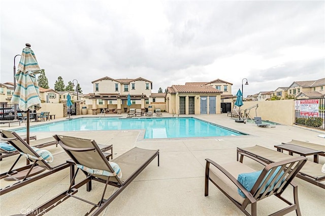 pool featuring a patio area, fence, and a residential view