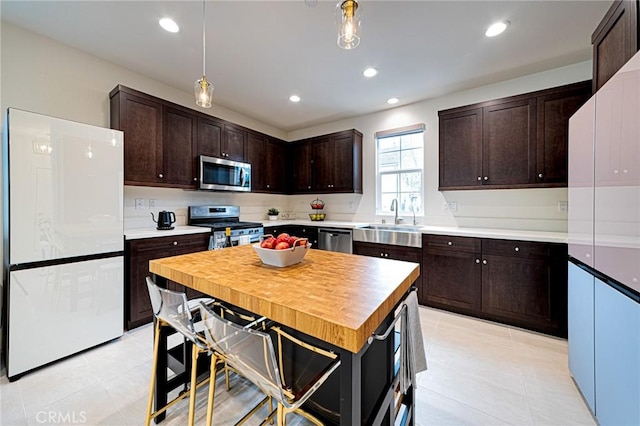 kitchen with a sink, appliances with stainless steel finishes, recessed lighting, and dark brown cabinets