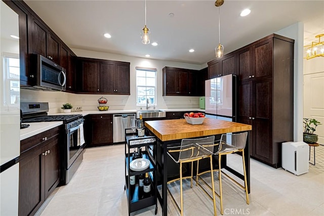 kitchen with dark brown cabinets, recessed lighting, appliances with stainless steel finishes, hanging light fixtures, and a sink