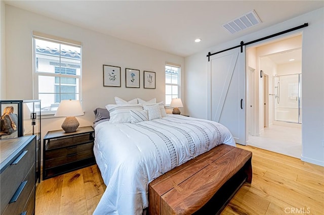 bedroom featuring visible vents, light wood finished floors, baseboards, recessed lighting, and a barn door